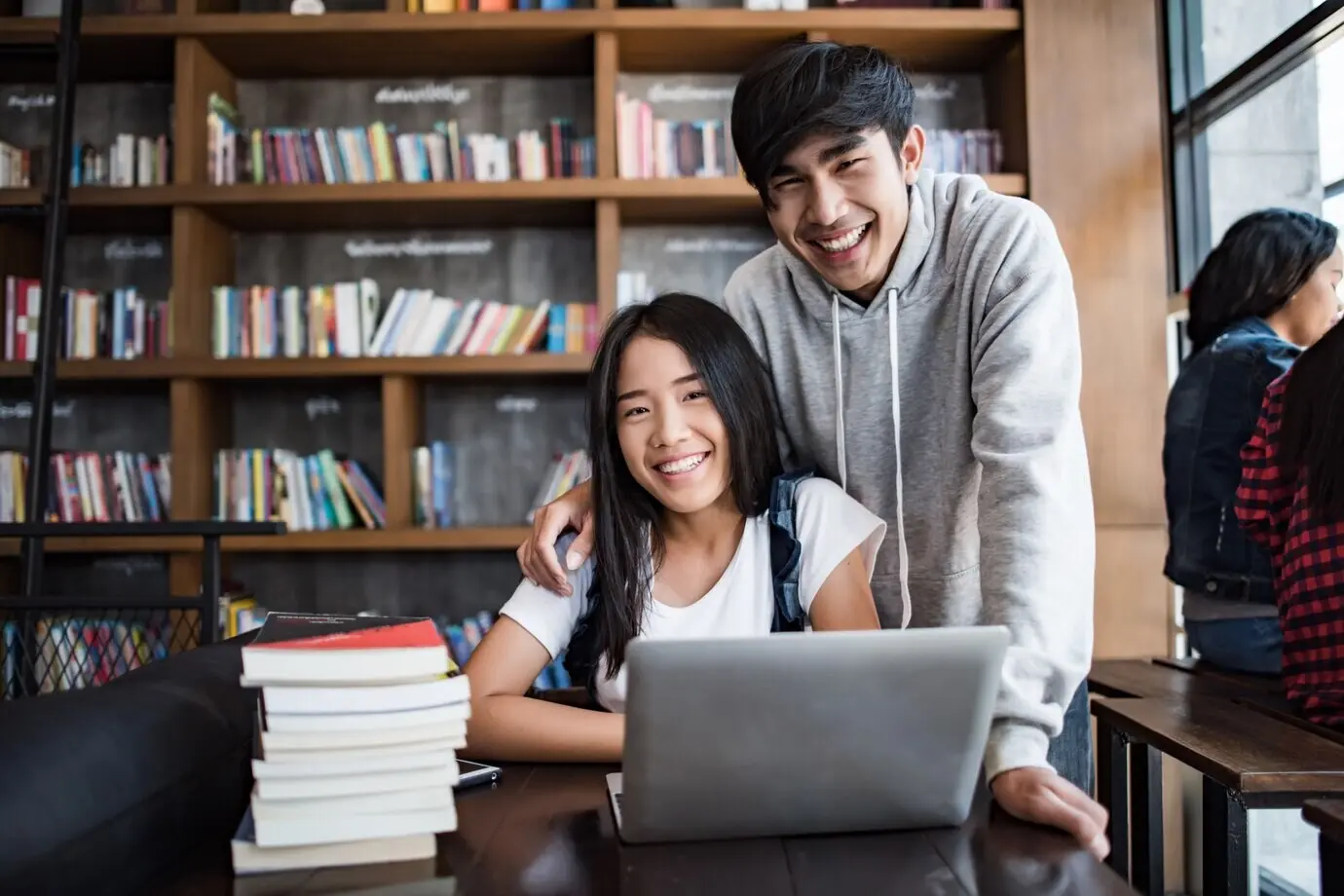 Eine Gruppe fröhlicher befreundeter Studierender, die im Café über Wissen sprechen.